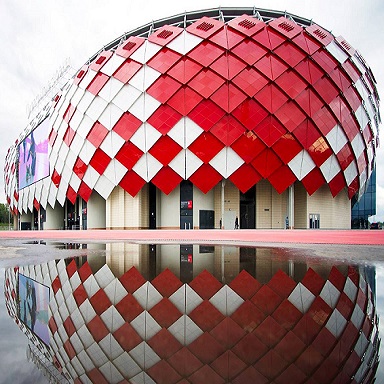 Красно-белое здание сферической формы с отражением в воде перед ним